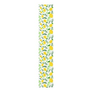 May include: A long, rectangular table runner featuring a repeating pattern of bright yellow lemons and vibrant green leafy sprigs set against a crisp white background. The design is evenly distributed across the entire length of the fabric.