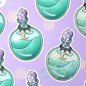 Könnte beinhalten: Sechs tealblaue Glas-Tränkflaschen mit silbernen Deckeln und Kristallstopfen. Jede Flasche ist mit einer glitzernden blauen Flüssigkeit gefüllt und hat einen Halbmond und Wolken auf der Vorderseite.