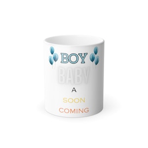 Op de afbeelding: Witte keramische mok met blauwe ballonnen en de tekst "A Boy Baby is Coming" in zwart, geel en oranje.