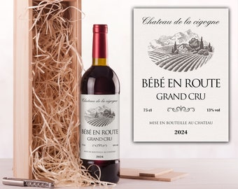 May include: A wooden box with straw filling, containing a bottle of red wine with a label that reads "Chateau de la cigogne, Bebe en Route Grand Cru, 75 cl, 13% vol, Mise en bouteille au chateau, 2024".