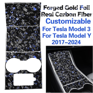 May include: A set of black and blue carbon fiber interior trim pieces for a Tesla Model 3 or Model Y. The trim pieces are customizable and include a cup holder and a center console cover. The text "Forged Gold Foil Real Carbon Fiber Customizable For Tesla Model 3 For Tesla Model Y 2017-2024" is printed on the image.