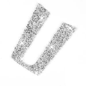 May include: A silver letter U made of rhinestones. The letter is on a white background.