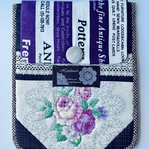 Puede incluir: Una funda para teléfono hecha a mano con un diseño de patchwork que presenta una impresión floral, encaje blanco y negro y una tela morada con el texto "Potter the fine Antique Shop" y "Schedule Now! Call (5)-125-7913".