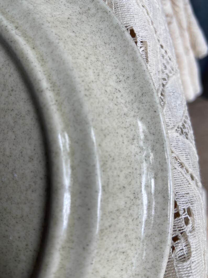 Pode incluir: Close-up de um prato de cer&acirc;mica verde claro com acabamento salpicado. O prato tem uma borda ligeiramente ondulada.