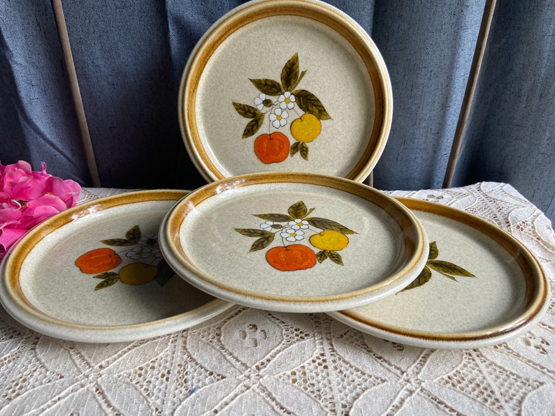 Pode incluir: Conjunto de quatro pratos de jantar de cer&acirc;mica castanho e bege com um design floral com fruta laranja e amarela.