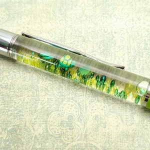 May include: A green pen with a clear barrel filled with green and yellow glitter and small turtle charms.