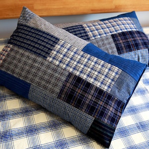May include: Two blue and white checked pillowcases with a patchwork design. The pillowcases are made of different fabrics and have a variety of blue and white checked patterns.