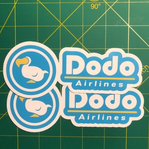 May include: A collection of stickers featuring the "Dodo Airlines" logo. The stickers have a white and yellow dodo bird in a blue circle, and the words "Dodo Airlines" in white with a yellow underline.