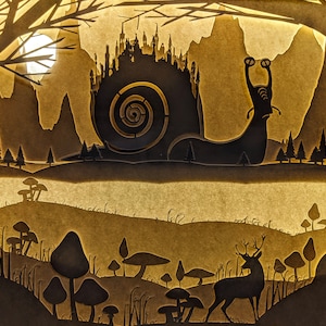 May include: A papercraft shadow box with a silhouette of a snail carrying a city on its back. The snail is in a forest setting with trees, mushrooms, and a deer.