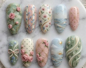 Puede incluir: Un juego de diez uñas postizas en forma de almendra con intrincados diseños en 3D que incluyen rosas rosas esculpidas, patrones florales pintados a mano, detalles de celosía dorada, olas oceánicas con soles dorados, lunares y cintas delicadas.