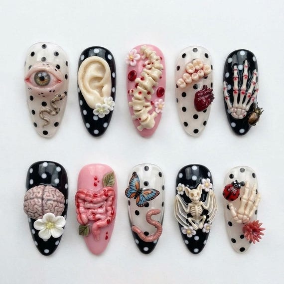 Hand-painted press-ons featuring actual anatomical art — skeletons, eyes, butterflies, and 3D oddity details that look like wearable curiosity cabinet specimens.
