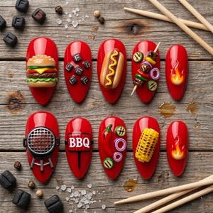 May include: A set of ten red press-on nails featuring 3D barbecue-themed decorations including a burger, hot dog, skewer, grill, corn on the cob, chili pepper, flames, and a sign with the text BBQ, arranged with scattered black cubes and salt.