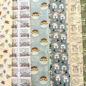 May include: A collection of patterned fabrics featuring designs inspired by a popular science fiction series. The patterns include images of a character, text that says "SNACK", "PROTECT", "ATTACK", and "THIS IS MY GOOD SIDE", and other related graphics. Colors include white, blue, green, and tan.