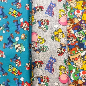 May include: Three different fabrics featuring Super Mario characters. One is teal with Mario and Luigi, another is gray with various characters, and the third is a colorful pattern with many characters.