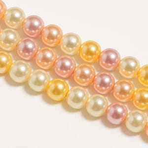 May include: A strand of pearl-like beads in three colours: cream, light pink, and pale yellow. The beads are arranged in a staggered pattern, creating a visually appealing design.