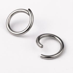 Op de afbeelding: Twee zilveren springringen, een gesloten en een open, op een witte achtergrond.