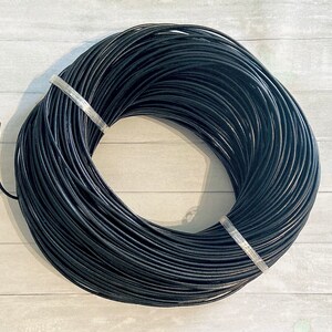 May include: A spool of black leather cord. The cord is wound tightly around the spool, creating a smooth, even surface.