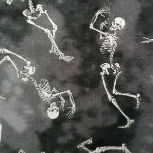 May include: Black and white fabric with a repeating pattern of skeletons. The skeletons are in various poses, some are dancing, some are standing, and some are lying down.