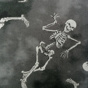 May include: Black and white fabric with a repeating pattern of skeletons. The skeletons are in various poses, some are standing, some are lying down, and some are reaching up. The fabric has a textured, almost fuzzy look.