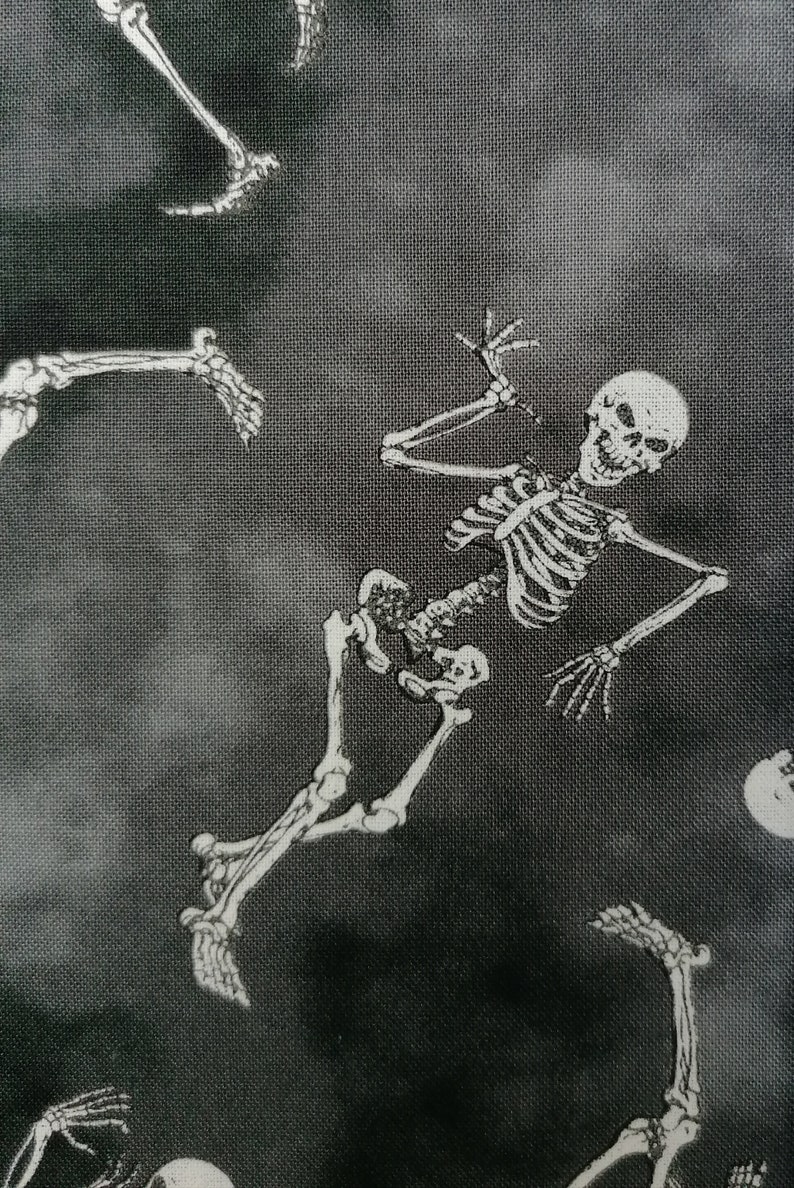 May include: Black and white fabric with a repeating pattern of skeletons. The skeletons are in various poses, some are standing, some are lying down, and some are reaching up. The fabric has a textured, almost fuzzy look.