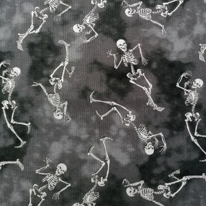May include: A black and white fabric with a repeating pattern of skeletons dancing. The skeletons are white and the background is a dark grey with a mottled, tie-dye effect.