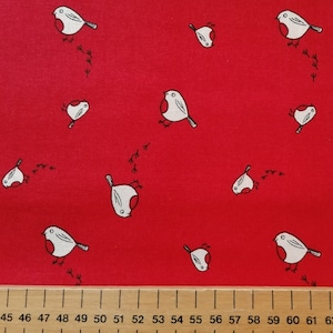 May include: Red fabric with a repeating pattern of white robins with red breasts. The robins are facing left and have small black feet and a black tail. The robins are leaving a trail of small black footprints.