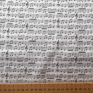 May include: White fabric with a black musical note pattern. The fabric features a repeating pattern of musical notes and clefs.