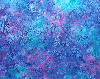 May include: A colourful batik fabric with a floral design. The fabric features a pattern in shades of blue, purple, and pink. The material has a textured look, with a ruler along the bottom edge showing measurements in centimetres.