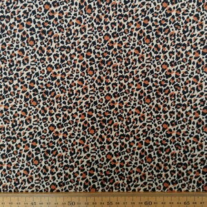 May include: A beige fabric with a brown and black leopard print pattern.
