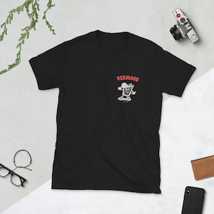 Può includere: Maglietta nera con un'illustrazione di cartone animato di un bicchiere di vermut con una fetta di limone. Il testo "VERMOOD" è stampato in rosso sopra l'illustrazione.