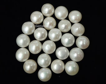 May include: A collection of 20 white round pearl cabochons. The pearls are smooth and glossy, and they are arranged in a loose circle.