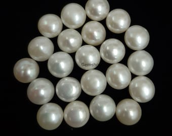 May include: A collection of lustrous, round, white pearls against a black background. The pearls have a smooth, reflective surface, and varying sizes. The image is well-lit, highlighting the pearls' natural sheen. The pearls are arranged in a scattered pattern.