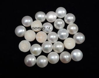 May include: A collection of lustrous, white pearls of varying sizes, some with a visible iridescent sheen. The pearls are scattered on a black background. The text "GEMSHOUSE" is visible on some of the pearls.