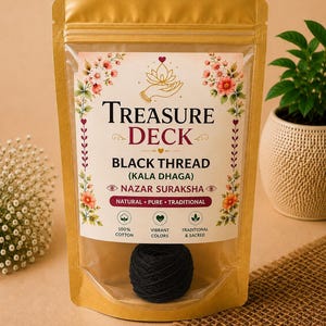 Puede incluir: Una bolsa dorada con cierre que contiene un ovillo de hilo negro. La etiqueta dice Treasure Deck, Black Thread (Kala Dhaga), Nazar Suraksha, Natural, Pure, Traditional, 100% Cotton, Vibrant Colors y Traditional & Sacred.