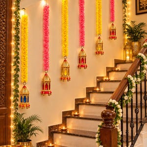 May include: A staircase decorated with hanging garlands of yellow and pink flowers, each ending in a metallic lantern with colored glass panels. Small lit candles are placed on each step, and a floral vine wraps around the wooden handrail.