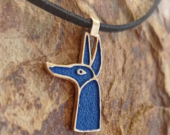 May include: A blue and gold pendant necklace featuring an Anubis head design. The pendant is on a black leather cord.