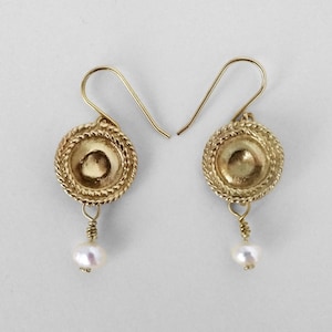 May include: Gold earrings with a round, textured disc and a single pearl dangling from each earring.
