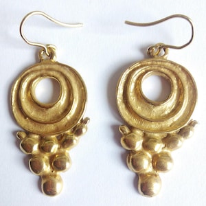 May include: Gold tone earrings with a circular design and a dangling cluster of round beads.