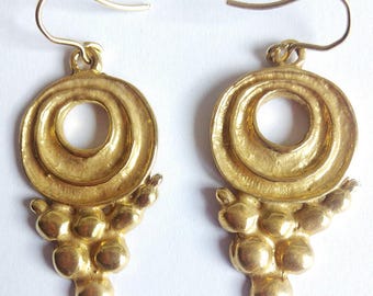 May include: Gold tone earrings with a circular design and a dangling cluster of round beads.