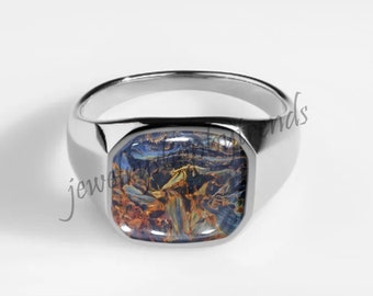 May include: A silver signet ring with a square-shaped blue and orange stone set in the center. The stone has a swirling pattern.