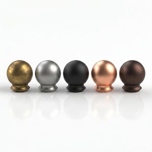 May include: Five decorative finials with spherical tops and rounded bases, arranged in a row. The finishes include antique brass, silver, black, copper, and bronze. The finials are displayed against a white background.