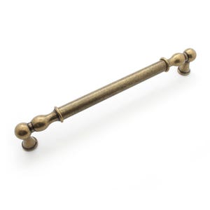 May include: Antique brass cabinet pull with a central bar and decorative ball-shaped ends. The hardware is approximately 20 cm long, with a warm, aged finish. Suitable for kitchen or bathroom cabinets.