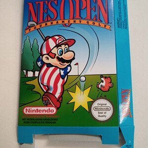Pode incluir: Uma caixa de jogo Nintendo NES azul e branca com um personagem de desenho animado vestindo um traje vermelho, branco e azul jogando golfe. A caixa tem o texto "NES OPEN TOURNAMENT GOLF" na frente. A caixa também tem um logotipo "Nintendo Seal of Quality".
