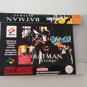 Puede incluir: Una caja de cartucho de juego Super Nintendo negra para Batman Returns. La caja presenta un fondo negro con un collage de imágenes de la película, incluyendo Batman, Catwoman y el Pingüino. El texto "Batman Returns" está impreso en blanco en la caja.