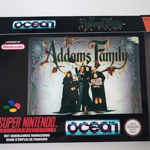 Peut inclure: Une boîte de jeu Super Nintendo noire avec un logo Nintendo coloré. La boîte présente une image des personnages de la famille Addams du film. Le titre du jeu est "The Addams Family" et le jeu est sous licence Nintendo. La boîte est fabriquée par Ocean.