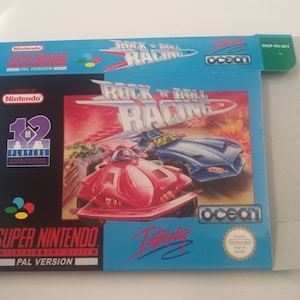 Puede incluir: Una caja de juego de Super Nintendo azul y blanca con el título "Rock 'n' Roll Racing" y una imagen de dos coches futuristas corriendo en una pista. La caja es para la versión PAL del juego.