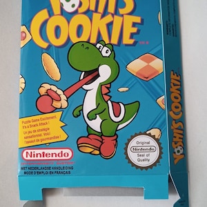Könnte beinhalten: Eine blaue und gelbe Schachtel für das Nintendo Entertainment System-Spiel Yoshi's Cookie. Die Schachtel zeigt ein Cartoon-Bild von Yoshi, einem grünen Dinosaurier, der einen Keks isst. Der Text auf der Schachtel lautet "Yoshi's Cookie" und "Nintendo Entertainment System".