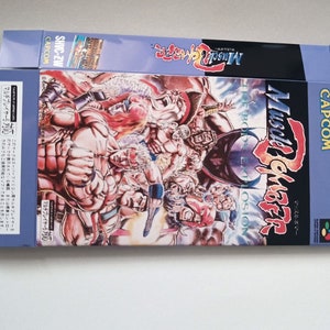 Peut inclure: Une boîte bleue et blanche pour le jeu vidéo Super Nintendo Entertainment System "Muscle Bomber: The Body Explosion". La boîte présente une illustration colorée d'hommes musclés en position de combat. Le jeu est édité par Capcom.
