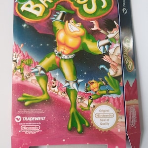 Op de afbeelding: Een roze en blauwe Nintendo-gamecartridgebox met een groen, geel en rood cartoon kikkerpersonage met de tekst "BATTLETOADS" op de voorkant. De doos heeft de tekst "TRADEWEST" aan de zijkant en het Nintendo-kwaliteitszegel aan de voorkant.