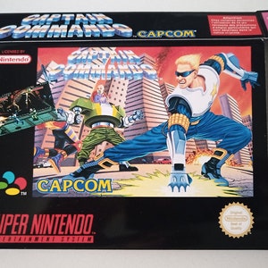 Könnte beinhalten: Eine Super Nintendo Entertainment System-Spielbox für Captain Commando. Die Box hat einen schwarzen Hintergrund mit einem bunten Bild der Spielfiguren. Der Spieltitel ist in Weiß auf der Box gedruckt, zusammen mit dem Capcom-Logo.